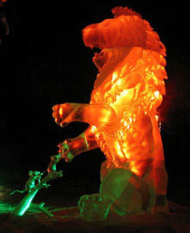 Colorful ice sculpture of “A Little Help,” ice carving of a lion being helped by two small mice, who are taking a thorn out of his paw. Viewed at night and lit with colorful light. Heather Brown and Steve Brice’s entry in Ice Alaska’s World Ice Art Event, 2007. Photo by Heather Brown