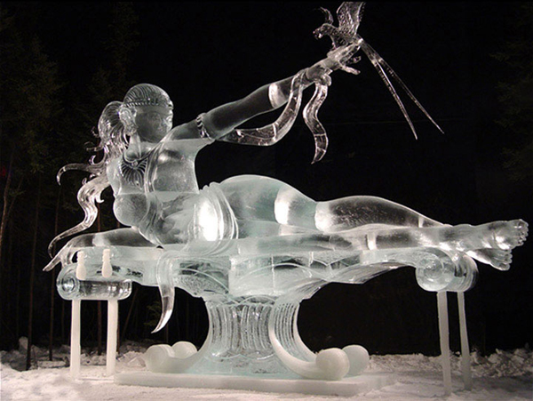 “Birth of Blue Bird,” an ice sculpture of a woman on a pedestal, lying on her side. She is pointing to the sky with a bird perched on her fingertips. By Junichi Nakamura and team (Junichi Nakamura, Daniel Reboltz, Shinichi Sawamura and Hitoshi Shimmoto) for Ice Alaska event.